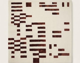 May include: A square area rug featuring a cream-colored background with a scattered pattern of dark brown rectangular blocks of varying lengths and widths arranged in a grid-like formation across the entire surface of the textile floor covering.