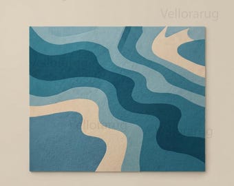 May include: A rectangular area rug featuring a wavy, abstract pattern in shades of deep navy blue, medium blue, light blue, and soft beige. The design consists of fluid, organic bands that flow across the surface, creating a layered effect.