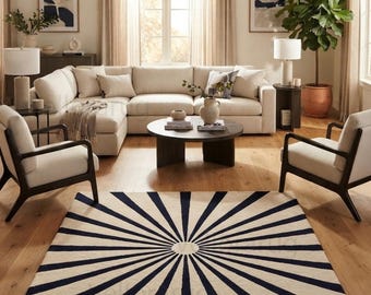 May include: A rectangular area rug featuring a cream-colored background with a dark navy blue sunburst pattern radiating from a central circular point. The design consists of thin, dark lines extending outward to the edges of the rug.