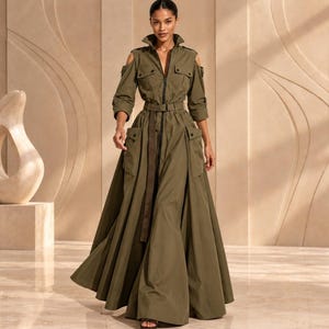 Könnte beinhalten: Ein olivgrünes Maxikleid mit Kragen, durchgehendem Frontreißverschluss und Schulterausschnitten. Das Kleidungsstück verfügt über lange Ärmel mit geknöpften Manschetten, zwei große Pattentaschen auf der Brust und einen passenden Stoffgürtel.