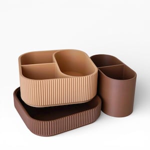 Peut inclure: Un ensemble de trois organisateurs de bureau modulaires avec une texture extérieure côtelée. La collection comprend un plateau carré marron foncé, un récipient rectangulaire beige clair à trois compartiments et un porte-gobelet ovale marron foncé.