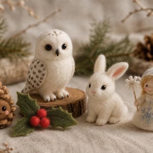 May include: A collection of needle-felted figures including a brown pinecone creature with a smiling face, a white snowy owl, a white rabbit, and a small angel doll wearing a hat and holding a star wand, accented by green holly leaves.