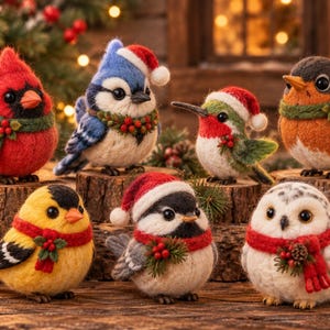 Op de afbeelding: Een verzameling van zeven naaldgevilte vogelbeeldjes, elk met een feestelijk accessoire zoals een kerstmuts of een rood-groene sjaal met hulstbessen. De vogels omvatten een kardinaal, een blauwe gaai, een kolibrie, een roodborstje en een uil.