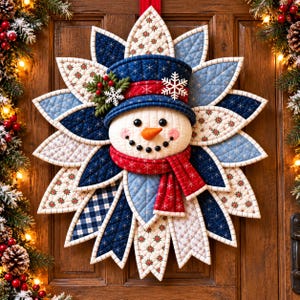 May include: A quilted fabric snowman wall hanging featuring a blue top hat, a red scarf, and a starburst of layered fabric petals in blue, white, and red patterns. The snowman has a carrot nose, black button eyes, and a stitched smile.