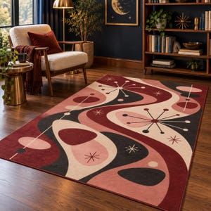 May include: A rectangular area rug featuring a repeating pattern of wavy bands in deep red, soft pink, and charcoal grey. The design includes stylised starburst shapes and circular motifs scattered across the surface, creating a rhythmic visual flow.