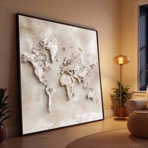 Può includere: Una grande opera d'arte da parete quadrata che presenta una mappa del mondo testurizzata in tre dimensioni nei toni del crema e del bianco sporco. I continenti sono in rilievo su uno sfondo neutro e liscio, racchiusi in una sottile cornice marrone scuro.