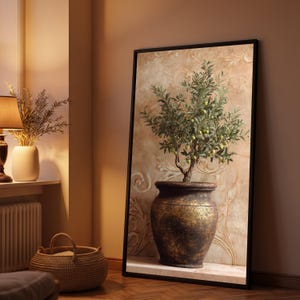 Op de afbeelding: Een ingelijste verticale wandkunstprint met een kleine olijfboom met groene vruchten in een grote, verweerde, donkerbronskleurige keramische pot. De achtergrond van het kunstwerk toont een getextureerde, beige muur met sierlijke krullen.