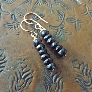 May include: A pair of dangle earrings with black faceted beads and gold hooks.