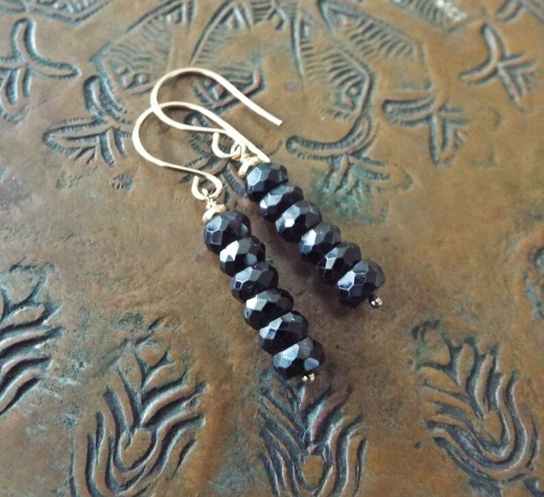 May include: A pair of dangle earrings with black faceted beads and gold hooks.