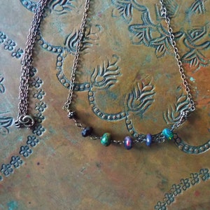 May include: A copper chain necklace with a delicate row of iridescent opal and black beads.