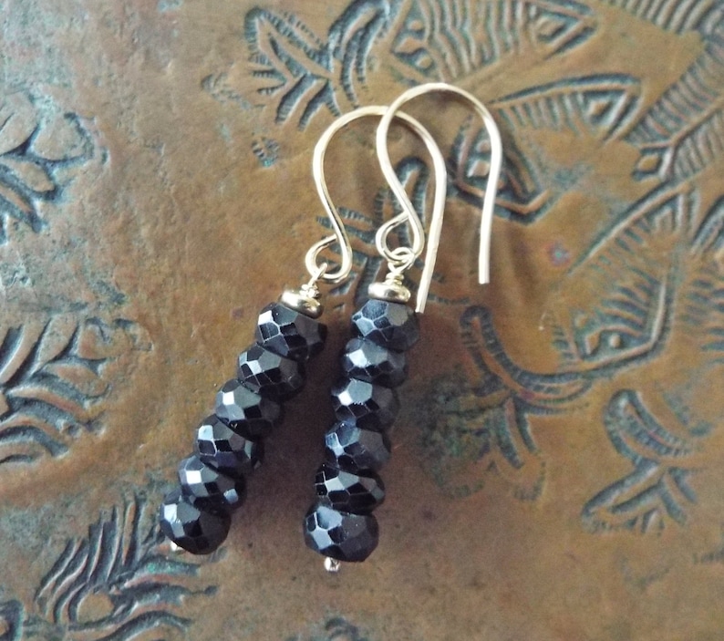 May include: A pair of silver dangle earrings with black faceted beads. The earrings are approximately 2 inches long.