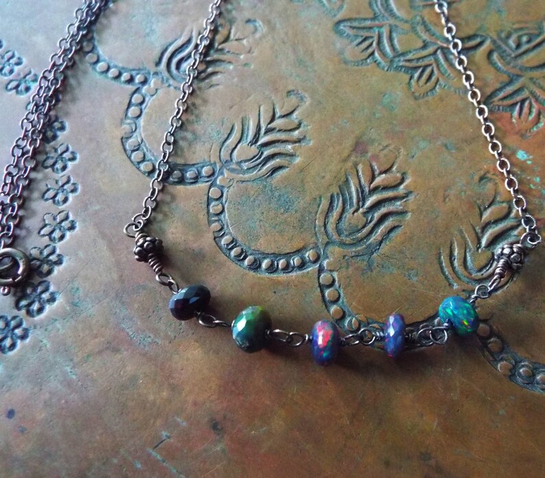May include: A copper chain necklace with five iridescent gemstone beads. The beads are a mix of dark purple, green, and opal.