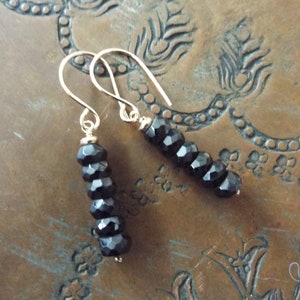 May include: A pair of dangle earrings with black faceted beads and gold hooks.