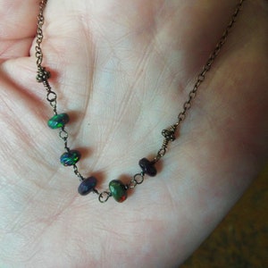 May include: A delicate necklace featuring a copper chain and iridescent black opal beads.