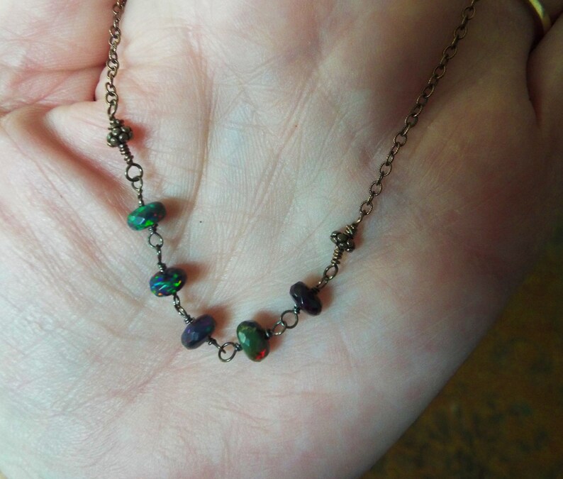 May include: A delicate necklace featuring a copper chain and iridescent black opal beads.