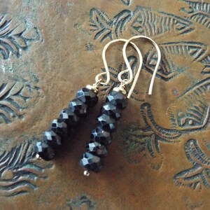May include: A pair of dangle earrings with black faceted beads and gold hooks.