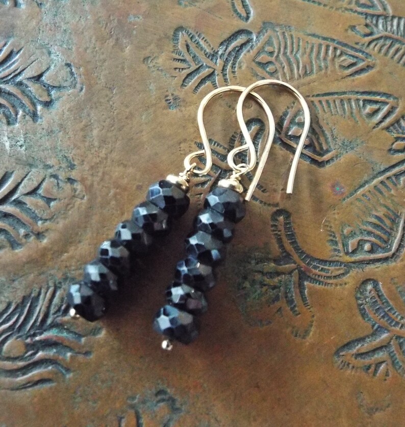 May include: A pair of dangle earrings with black faceted beads and gold hooks.