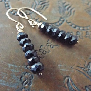 May include: A pair of dangle earrings with black faceted beads and gold hooks.