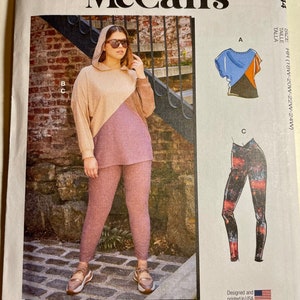 May include: McCall's sewing pattern M8244 featuring a hooded top and leggings. The pattern includes multiple view options. The image shows a woman wearing a color-blocked top and leggings. Designed and printed in the USA.