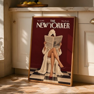 Pode incluir: Uma impressão emoldurada da capa da revista The New Yorker de 8 de novembro de 1975. A imagem mostra uma pessoa de roupão branco e turbante de toalha sentada numa sanita, a ler um jornal, contra uma parede vermelha e um chão de azulejos axadrezado.