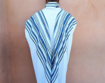 May include: A white prayer shawl with blue and brown stripes. The shawl is folded in half and draped over the shoulders of a person wearing a white hat.