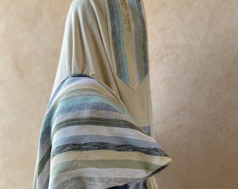 Puede incluir: Una chal de oración beige con rayas azules y verdes. La chal tiene una inscripción hebrea en el lateral.