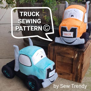 Puede incluir: Dos camiones de peluche, uno azul y otro naranja, con caras sonrientes y la palabra "MACK" en la parte delantera. Los camiones están sentados en una caja de madera. La imagen incluye el texto "TRUCK SEWING PATTERN ©".