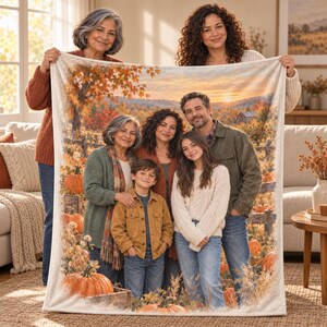 May include: A rectangular fleece blanket featuring a printed photograph of a family of five standing in an autumn landscape. The image displays a sunset over rolling hills, a wooden fence, and pumpkins in the foreground. The blanket has a soft texture.