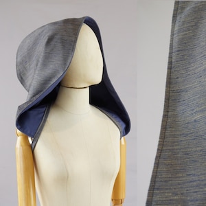 May include: A hooded garment made from a blue and grey striped fabric. The hood is lined with a solid blue fabric.