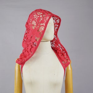 May include: A red lace hooded scarf with a delicate floral pattern. The scarf is draped over a mannequin's shoulders.