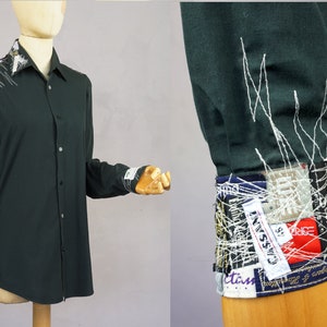 May include: A dark green long-sleeved shirt with white stitching on the cuffs. The cuffs are decorated with a patchwork of fabric scraps and labels, including the word "CLASSIC".