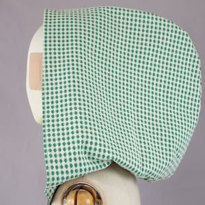 May include: A green and white gingham fabric hood. The fabric is a woven cotton with a small, repeated pattern.