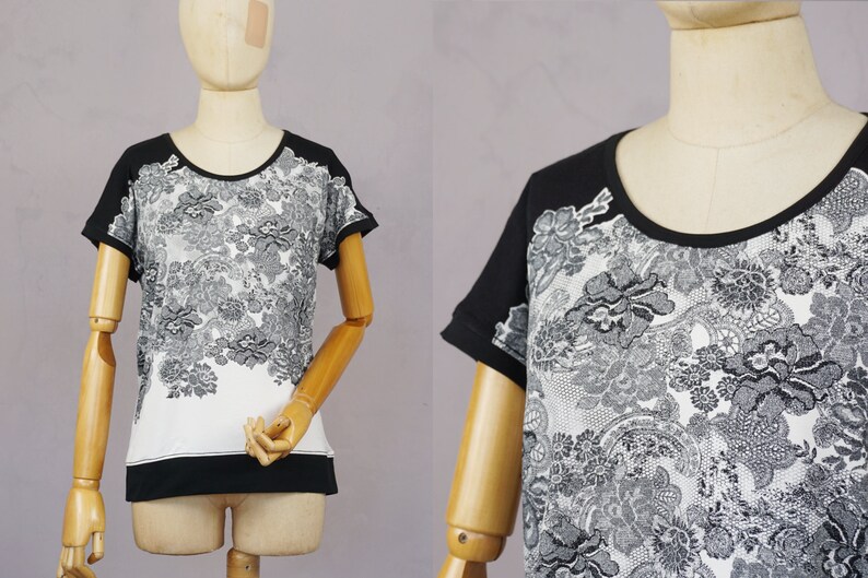 May include: A black and white short-sleeved shirt with a floral pattern. The shirt has a black collar and a white background with black floral designs.