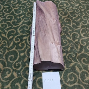May include: A light brown, textured piece of raw wood with a natural grain pattern. A white folding ruler is placed vertically along the side, showing a length of approximately 43 cm. A small white card with the text F-069 is visible.