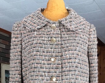 May include: A brown, white, and pink tweed jacket and skirt set with a double breasted closure and gold buttons.