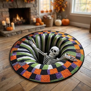 Puede incluir: Una alfombra redonda que presenta una ilusión óptica de un agujero profundo con un esqueleto emergiendo del centro. La alfombra tiene un borde a cuadros en naranja, morado, negro y verde, con rayas radiantes hacia el centro oscuro.