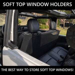 Könnte beinhalten: Ein schwarzer Halter für Softtop-Fenster, der hinter den Rücksitzen eines Fahrzeugs installiert ist. Der Text SOFT TOP WINDOW HOLDERS und THE BEST WAY TO STORE SOFT TOP WINDOWS! ist sichtbar. Der Halter ist ein flaches, dunkles Paneel an den Kopfstützen.