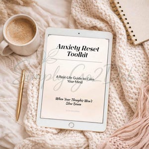 Puede incluir: Una tableta que muestra el texto Anxiety Reset Toolkit, A Real-Life Guide to Calm Your Mind, When Your Thoughts Won't Slow Down, y by SimplyGoDeb. La pantalla tiene un fondo beige claro con texto negro y una línea horizontal fina.