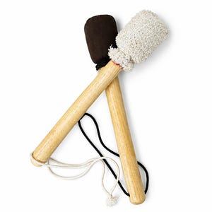 Könnte beinhalten: Zwei Schlägel mit hellen Holzgriffen, die sich kreuzen. Ein Schlägel hat einen glatten, dunkelbraunen, abgerundeten Kopf, während der andere einen strukturierten, cremeweißen Kopf aus gewebtem Stoff besitzt. Eine schwarze und eine weiße Kordel sind befestigt.