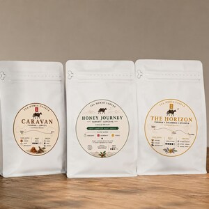 May include: Three white stand-up coffee pouches with circular labels. The labels feature the Tea Horse Coffee logo, a horse illustration, and text including Caravan, Honey Journey, and The Horizon, along with origin details and taste notes.