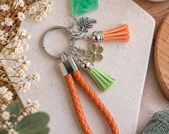 Orange and green keychain with braided wrist strap, pom-poms and flower, green resin pendant, bag accessory