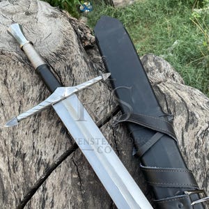 Könnte beinhalten: Ein silberfarbenes Metallschwert mit einer langen, zweischneidigen Klinge, einem kreuzförmigen Parier und einem umwickelten Griff. Neben dem Schwert liegt eine schwarze Lederscheide mit einem Schnallenriemen. Der Knauf ist sechseckig.