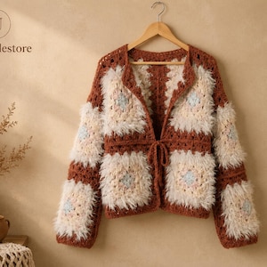 May include: A long-sleeved crochet cardigan featuring a patchwork design of rust-brown yarn squares and fuzzy, cream-colored textured squares with light blue centers. The garment has an open front with a thin tie closure at the waist.