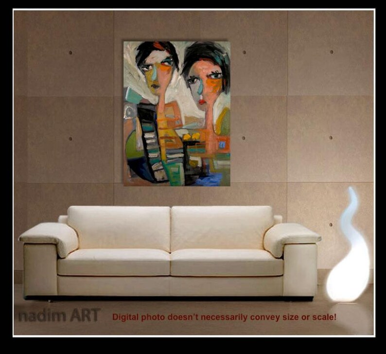 May include: Abstract painting of two women with colorful, stylized faces. The painting is framed and hanging on a wall above a white sofa.