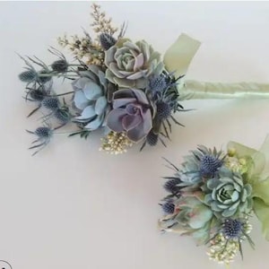May include: Two bouquets of succulents and thistle flowers. The larger bouquet has a light green ribbon. The smaller bouquet is on a white background.
