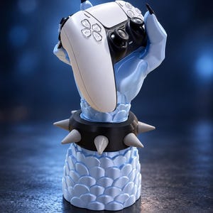 May include: A light blue monster hand sculpture with black claws holding a white and black video game controller. The base features a scale-like texture and a black wristband adorned with several pointed, light-colored spikes.