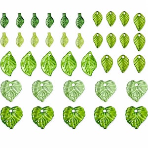 Peut inclure: Une collection de perles en verre vert translucide en forme de feuilles et de cœurs, disposées en rangées. Les perles présentent des textures nervurées détaillées et de petits trous au sommet pour l'enfilage, dans des tons de vert variés.