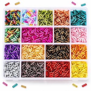 Puede incluir: Un contenedor de almacenamiento de plástico transparente con dieciséis compartimentos rectangulares llenos de pequeñas cuentas tubulares cilíndricas en una variedad de colores metálicos y translúcidos, incluyendo rojo, azul, verde, amarillo, morado, plata, oro y rosa.