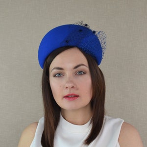 May include: A royal blue felt hat with a black net veil and black bead embellishments.
