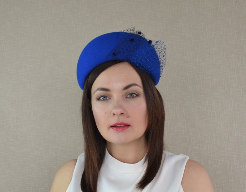 May include: A royal blue felt hat with a black net veil and black bead embellishments.